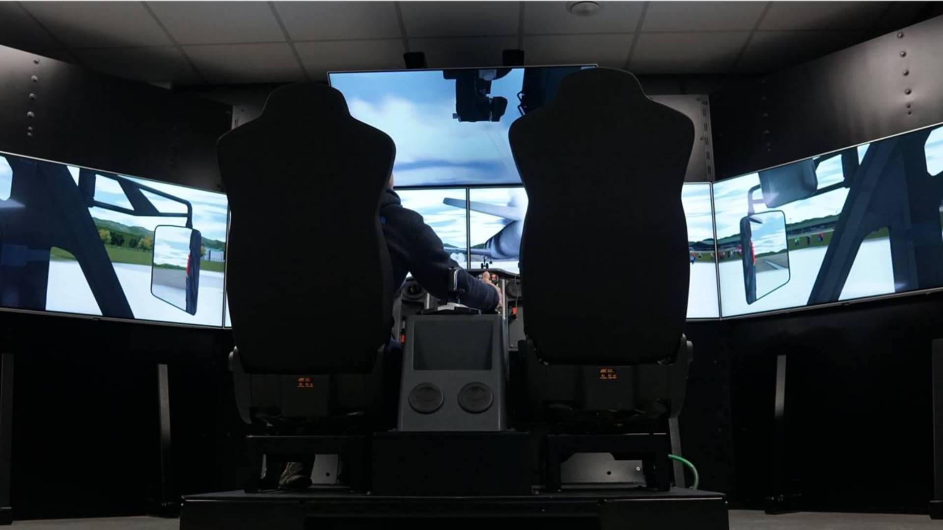 Firefighter operating the roof turret on the ARFF minicab simulator, 5 screens surround him for an immersive experience.