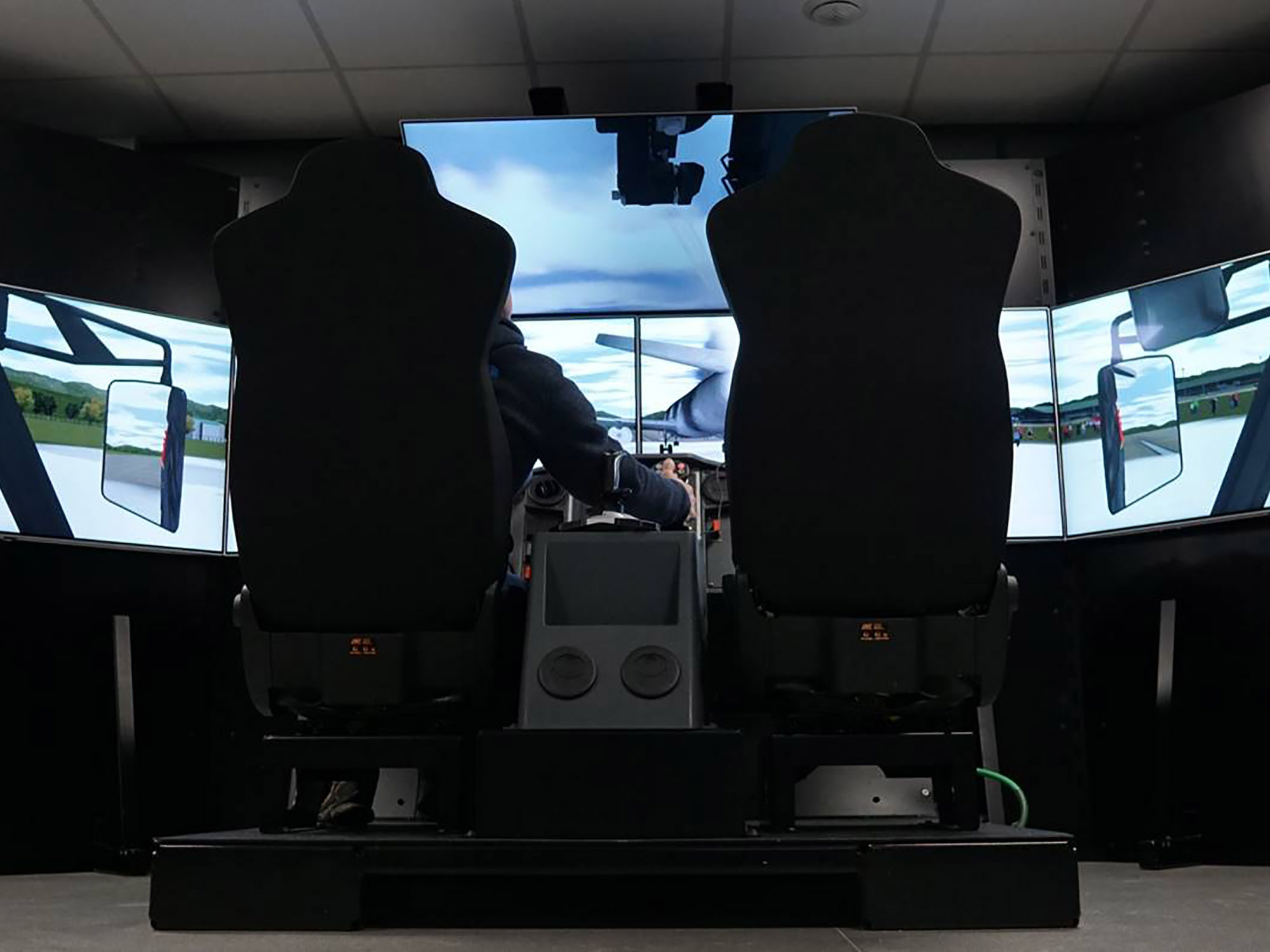 Firefighter operating the roof turret on the ARFF minicab simulator, 5 screens surround him for an immersive experience.